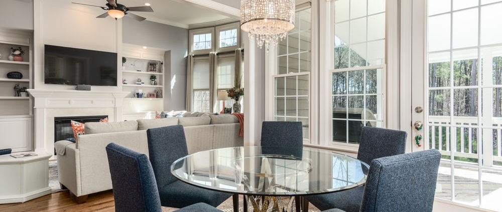 A well-lit dining room with a clear round table and blue chairs