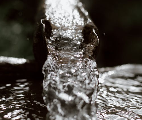 A metal rusted drain gutter draining water