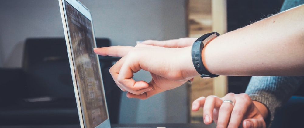 a person pointing their finger at the laptop